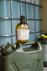 green canteen on top of a green 20L container with a metal grid background.