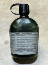 Green canteen bottle with black cap on a beige background