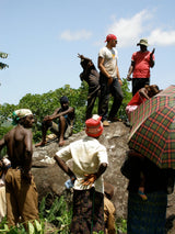 Group of people sitting on a rock with a clear blue sky and greenery in the background