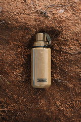 tan modcan tactical water bottle with 'TacValve' logo on a brown, textured surface