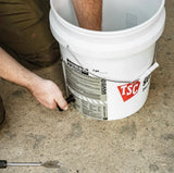 Person installing a black spigot on a white bucket on a concrete floor