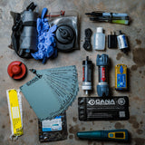 Collection of survival and outdoor gear items on a concrete surface
