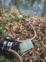 hose pulling water from a lake connected to a black cana provisions ar1 water pump on soil