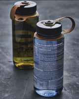 Two Nalgene bottles with black lids on a gray surface