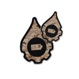 A pair of cana provisions geardrop logo shaped stickers featuring a tan digital style camouflage pattern, shown on a plain white background.