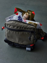 Fanny pack with medical equipment inside of it on a gray surface