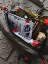 Fanny pack with medical equipment inside of it on a gray surface