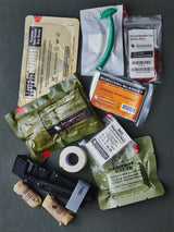 Collection of medical gear items including bandages, a blanket, and other medical supplies on a dark surface.
