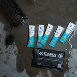 Cana Provisions personal rehydration kit with packets on a wet concrete surface with a clear nalgene water bottle nearby