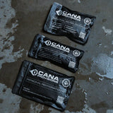 Three black pouch kits on a wet concrete surface