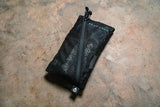 Black mesh pouch with a zipper on a textured surface