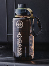 translucent tan water bottle with camouflage-patterned strap on a gray surface