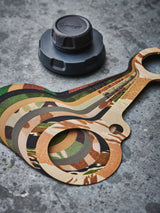 Set of camouflage-patterned water bottle cap tethers next to a black bottle cap on a grey background