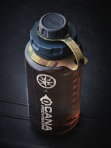 translucent tan water bottle with camouflage-patterned strap on a gray surface