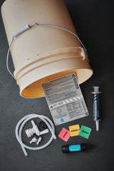 Bucket with a label and various small components on a dark surface