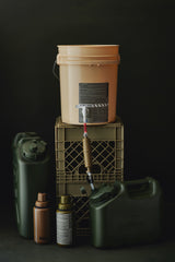 water filter components on a tan bucket with labels and hoses on a dark background