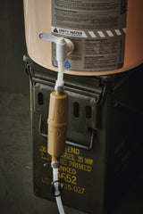 water filter components on a tan bucket with labels and hoses on a dark background