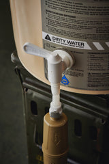 water filter components on a tan bucket with labels and hoses on a dark background