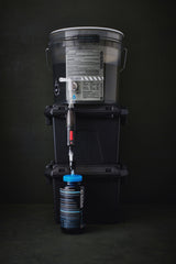 water filter components on a grey bucket with labels and hoses on a dark background