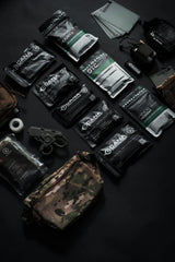 Collection of tactical gear including pouches, a knife, and other supplies on a dark surface.