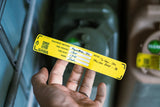 cana provisions water treatment record safety label with writing on it being held by a hand in front of blurred jerry cans in the background