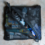 water filter gear in a black mesh pouch on a concrete surface.