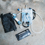 Hydration system components including a bladder,  and pouch on a concrete surface.